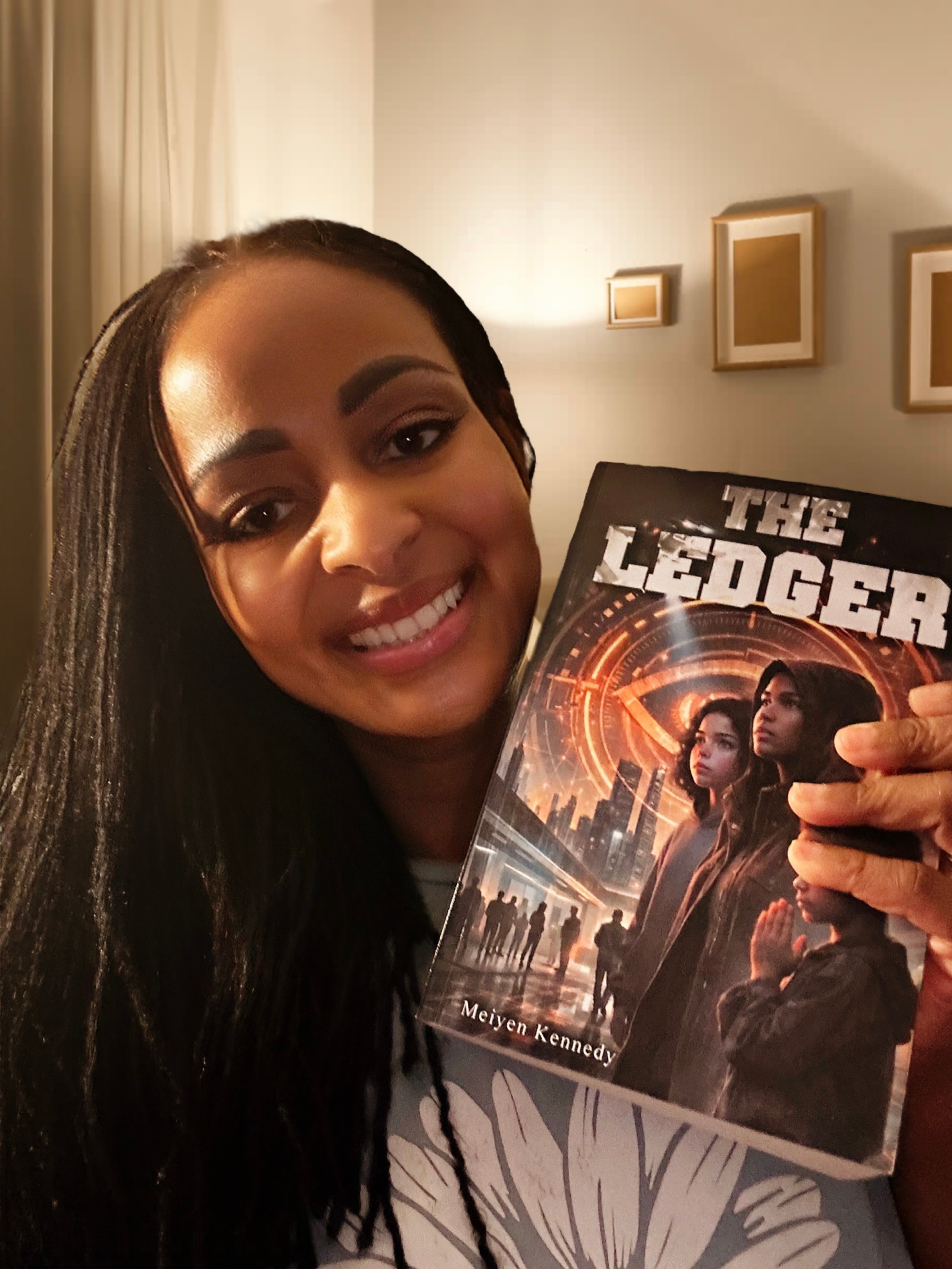 Meiyen Kennedy holding her new novel, The Ledger